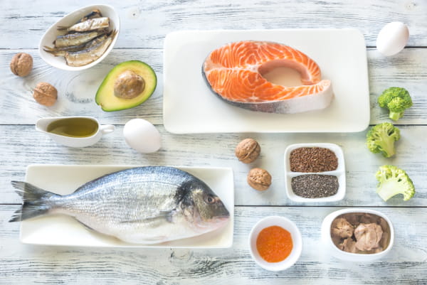 Benefícios do Ômega 3: sardinha, azeite, nozes e outros produtos em uma mesa.