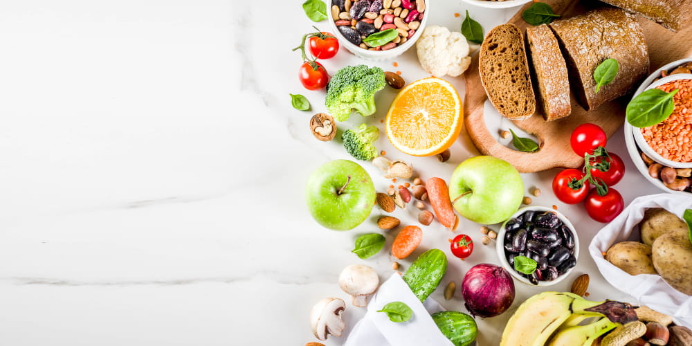 Fibras na dieta: frutas, legumes, grãos e pães sobre uma mesa.