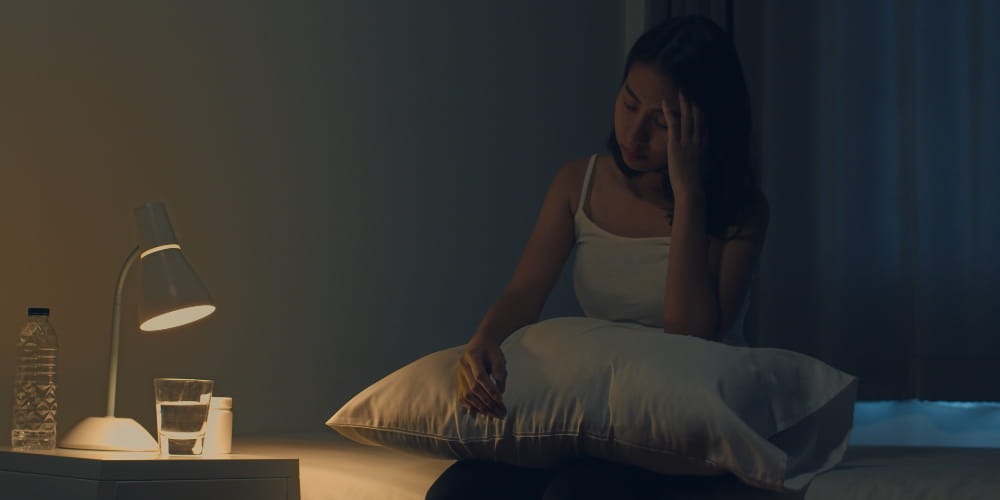 Saúde do sono - como você tem dormido: mulher com insônia sentada na cama.